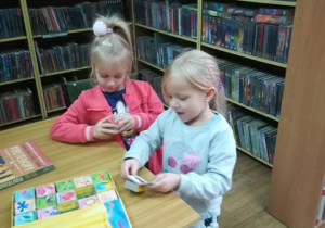 Dziewczynki oglądają najmniejsze w bibliotece książeczki.